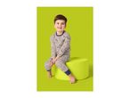 A young boy in dinosaur-patterned pajamas sits on a green stool, smiling.