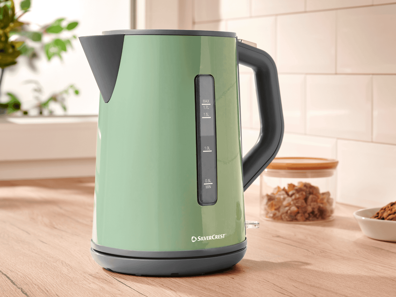 Eine mintgrüne Wasserkocher von Silvercrest steht auf einer Holzoberfläche.
