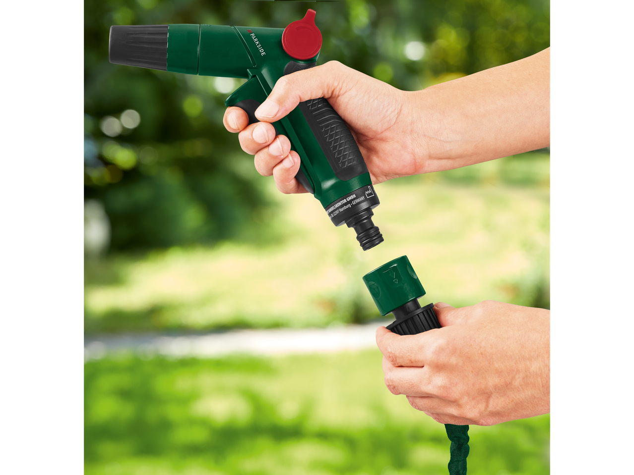A hand connects a Parkside hose fitting to a watering gun.