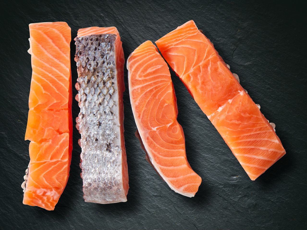 Frische Lachsfilets auf dunklem Schiefer.