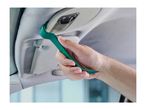 A person using a green plastic trim removal tool to pry open a car's overhead light console.