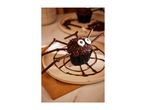 A chocolate spider cupcake with candy eyes and chocolate stick legs on a plate.