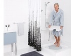 Smiling man in a bathrobe with a RIDDER® shower chair in a modern bathroom.