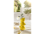 Vase en forme de citrons et vaisselle sur une table extérieure.