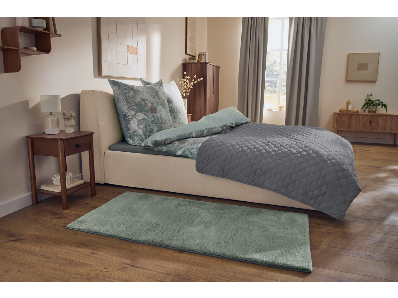 Quarto com cama com roupa de cama de microfibra acetinada com estampa botânica e edredão cinzento.