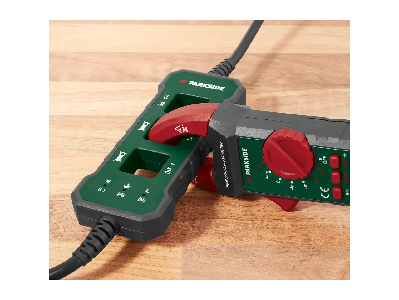 Two clamp meters on a wooden surface, one with a red dial and buttons, the other with a cable.