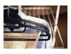Black clothes hangers with shirts and trousers hanging on a drying rack.