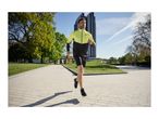 Man running in a black and neon yellow sports jacket and black shorts on a paved path.