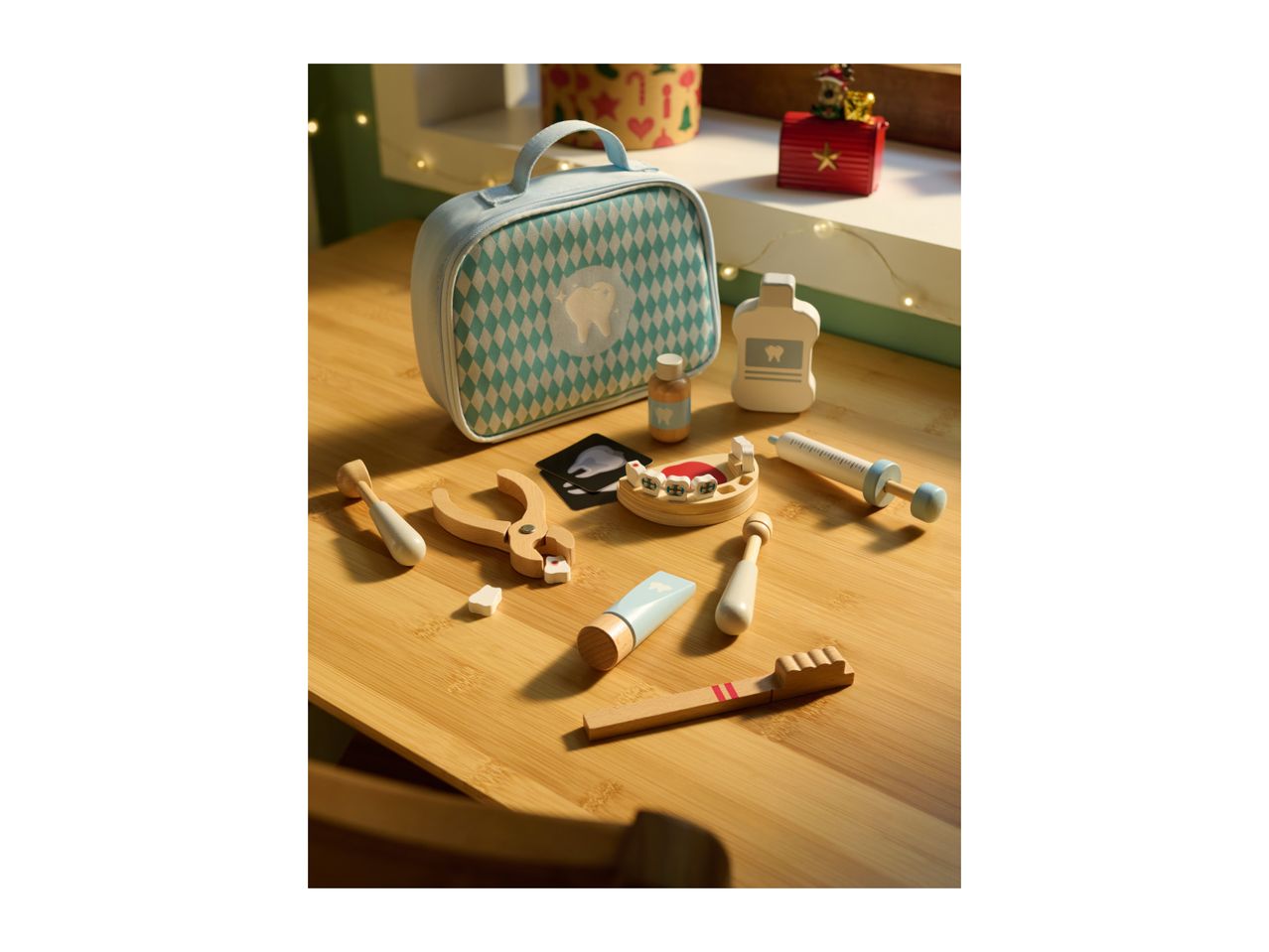 A wooden toy dentist set with a light blue bag, mouthwash, toothpaste, and dental tools on a wooden table.