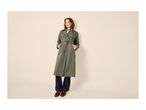 Woman in a long olive green trench coat, dark jeans, and brown loafers.