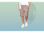 Homem modelando roupa casual: shorts bege e tênis brancos.
