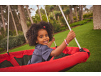 Happy child with curly hair on a red swing in a garden.