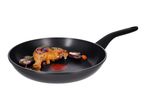 Frying pan with a cooked chicken leg, red onions, and herbs