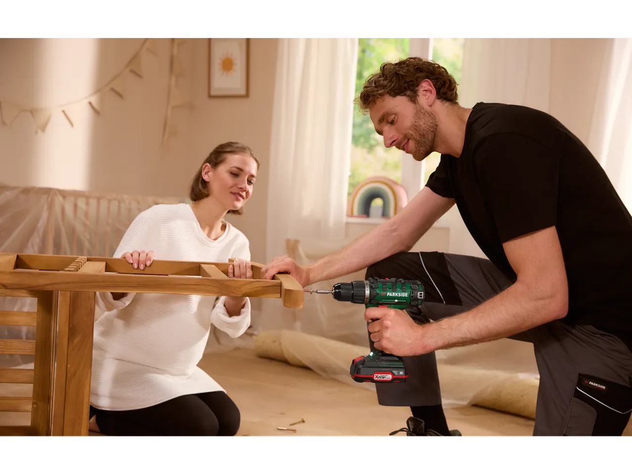 Couple assembling furniture using a Parkside drill.