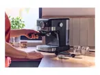 Person preparing coffee with an espresso machine on a wooden kitchen counter.