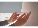 Pessoa instalando uma persiana de rolo dupla Livarno Home, mostrando o tecido e a barra