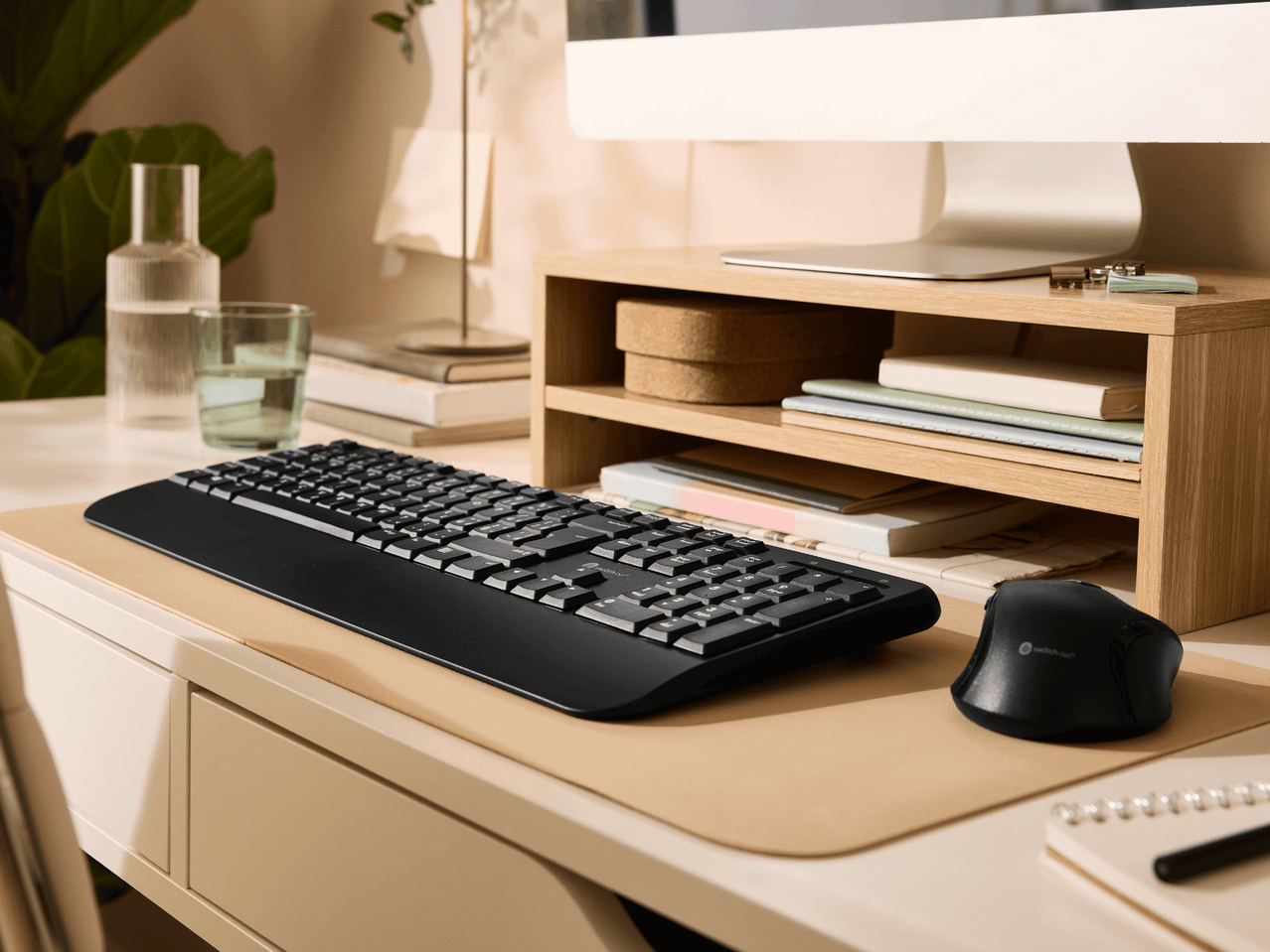 Un bureau d'ordinateur avec un écran, un clavier, une souris et des accessoires en bois.