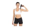 Woman in a white sports bra and black shorts using a black massage gun on her shoulder.