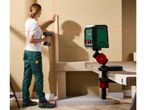 Laser level projecting lines, with a person working on a wall in the background.