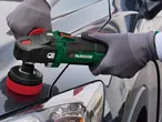 A person uses a Makita polisher to buff a car.