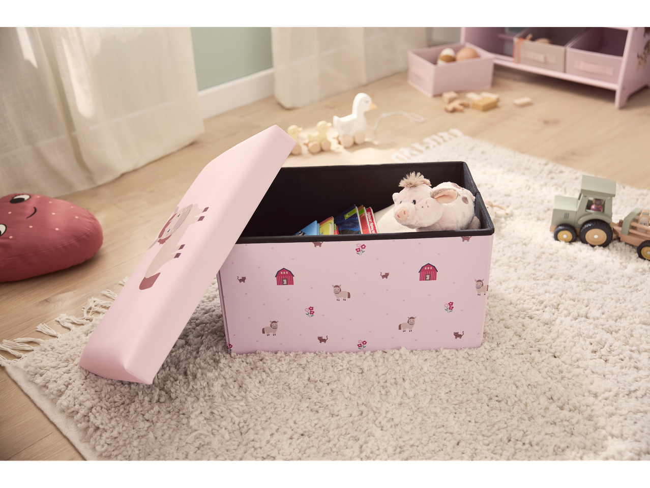 Caixa de arrumação rosa LIVARNO com animais da quinta, peluche e brinquedos de madeira num tapete.
