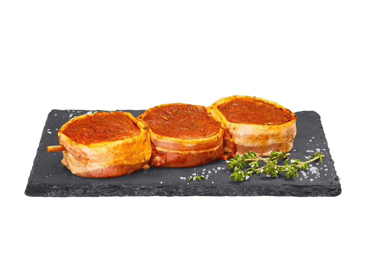 Tre medaglioni di maiale marinati, avvolti nel bacon, su una lastra di ardesia con timo.