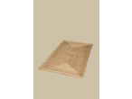 A rectangular natural jute rug with a braided texture, laid diagonally on a light beige surface.