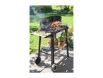 Charcoal barbecue with grilling meat and vegetable skewers, with side shelves and storage.