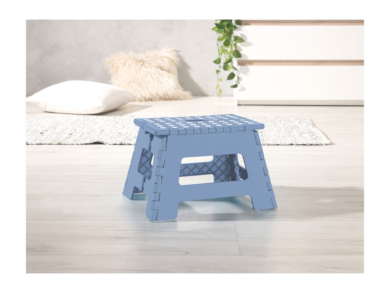 A light blue plastic folding step stool sits on a light wood floor.