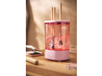 Pink makeup brush cleaner with brushes inside, filled with bubbly pink liquid, on a wooden surface.
