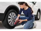 Woman using an Ultimate Speed tire inflator on a car tire.