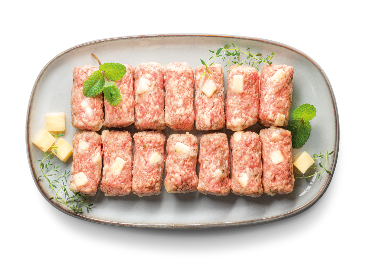 Сурови кебапчета с парченца сирене, гарнирани с мента и мащерка, върху овална чиния.