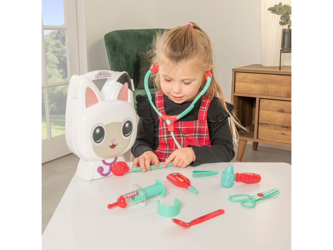 Menina a brincar com um kit de médico da Gabby's Dollhouse, com uma mala em forma de gato e brinquedos médicos.