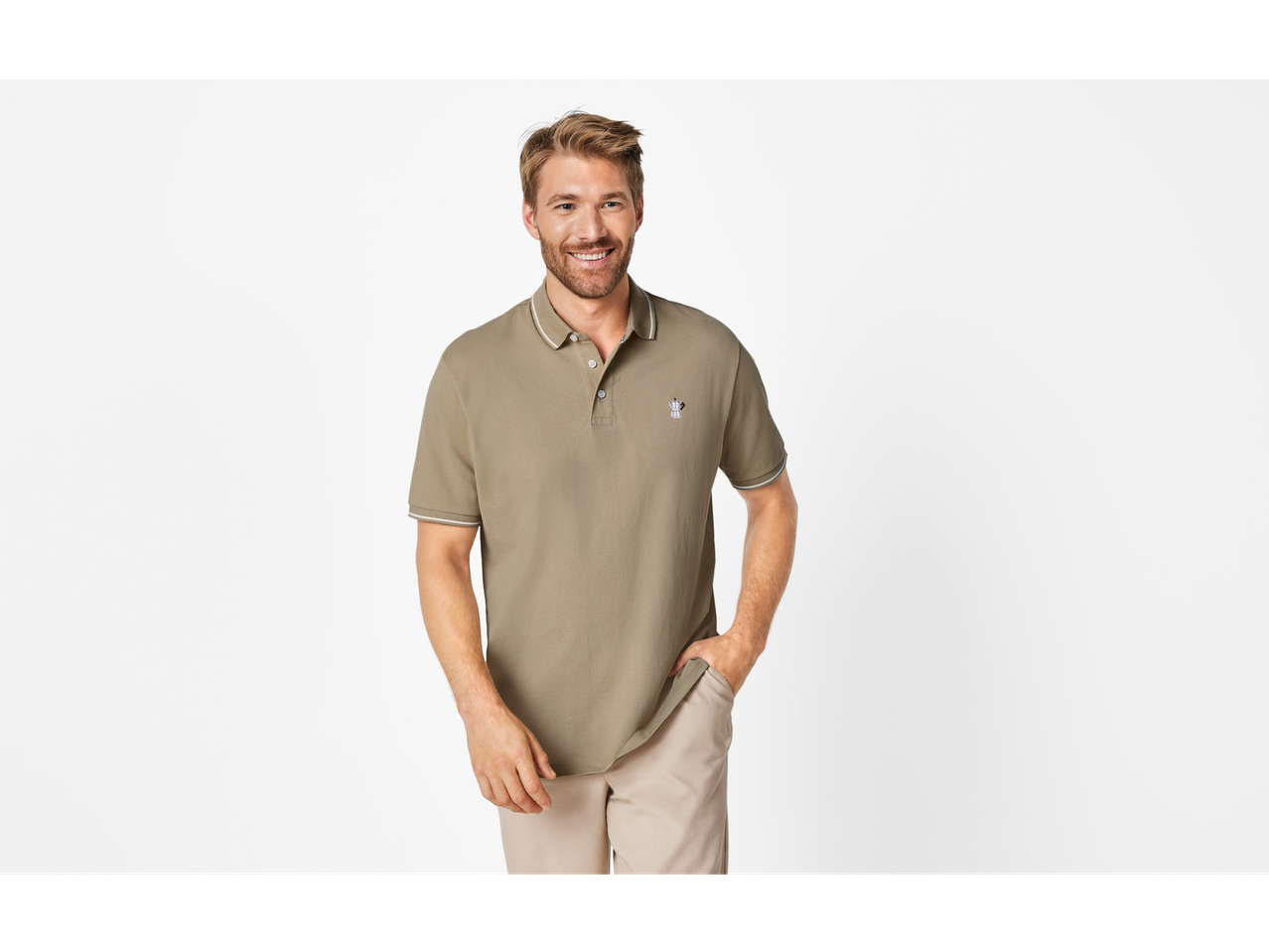 Muškarac se smiješi, nosi svijetlozelenu polo majicu kratkih rukava i bež hlače.