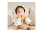 A baby in a white top and brown overalls chews on a yellow teether.