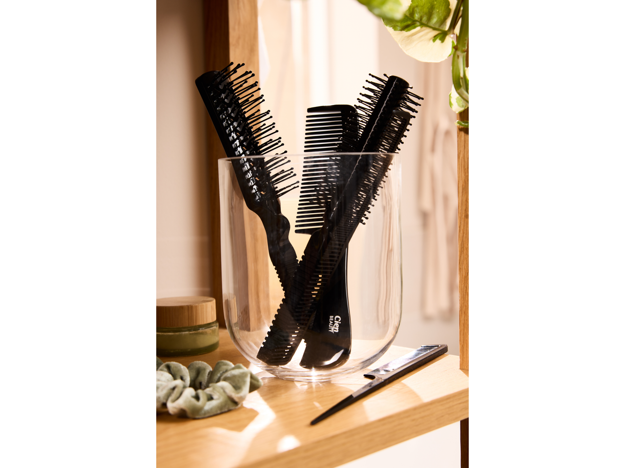 Cien Beauty: escovas e pentes pretos num recipiente de vidro, com produtos de beleza.
