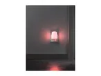 A red night light plugged into a wall outlet, illuminating a dark room.