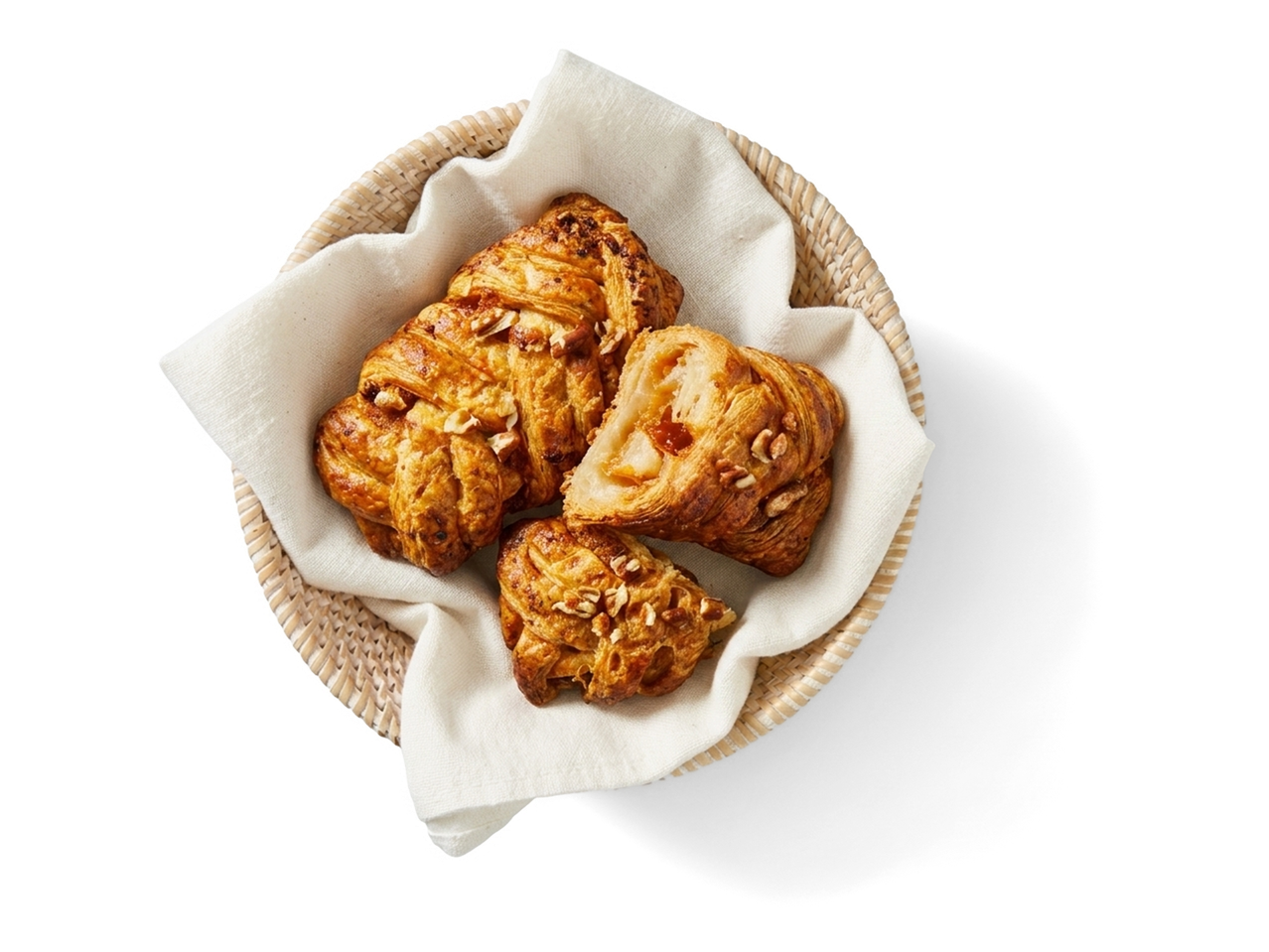 Mandje met versgebakken pecannotenbroodjes, waarvan één doorgesneden.