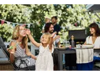 Familie se distrează cu bule de săpun la o masă în aer liber.