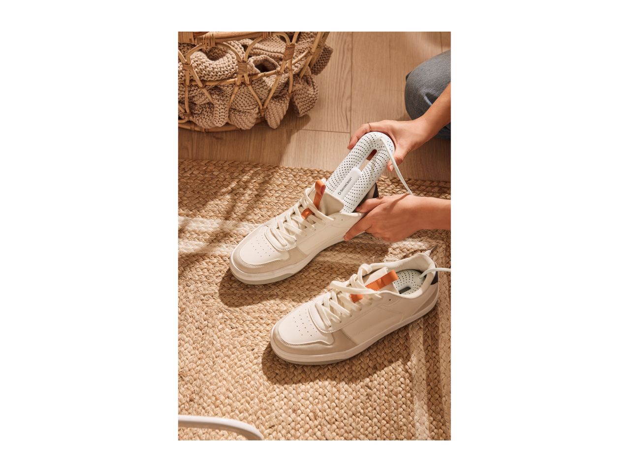 Person inserting a SilverCrest shoe dryer into a white sneaker on a woven rug.