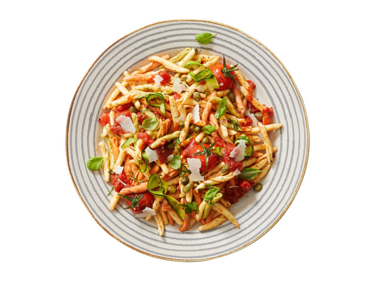 Pasta with tomato sauce, zucchini, capers, and basil on a striped plate.