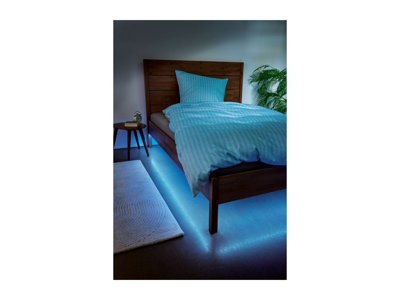 Bedroom with wooden bed, blue striped bedding, and blue under-bed lighting.