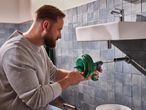 Férfi duguláselhárító spirállal tisztítja a mosdó lefolyóját.