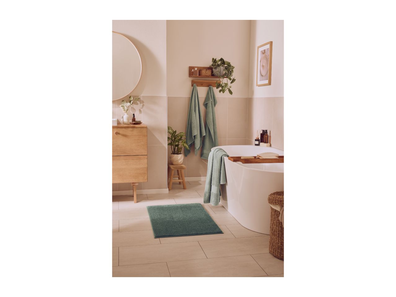 A modern bathroom with a white bathtub, wooden vanity, and green bath mat and towels.