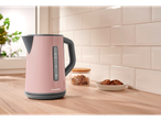 A pink SilverCrest kettle sits on a light wood countertop in a kitchen.