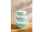 Stack of three mint green mixing bowls with white lids on a wooden surface.
