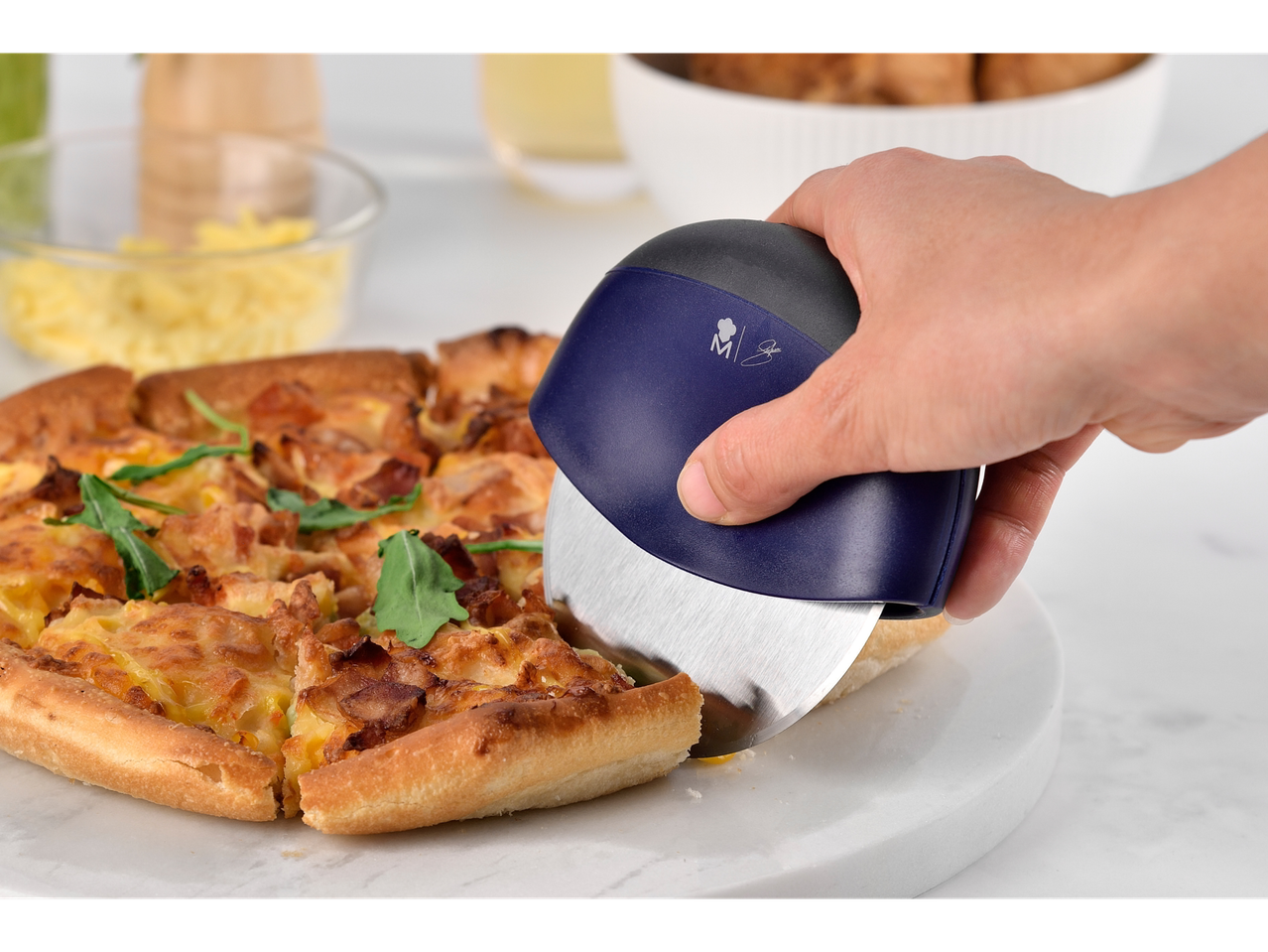 Pizza wird mit einem blauen Maestro-Pizzaroller geschnitten.