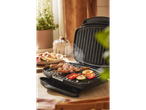 A black contact grill cooks chicken skewers and vegetables.