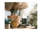 A terracotta pot wrapped in burlap and tied with green twine next to a spool of string.