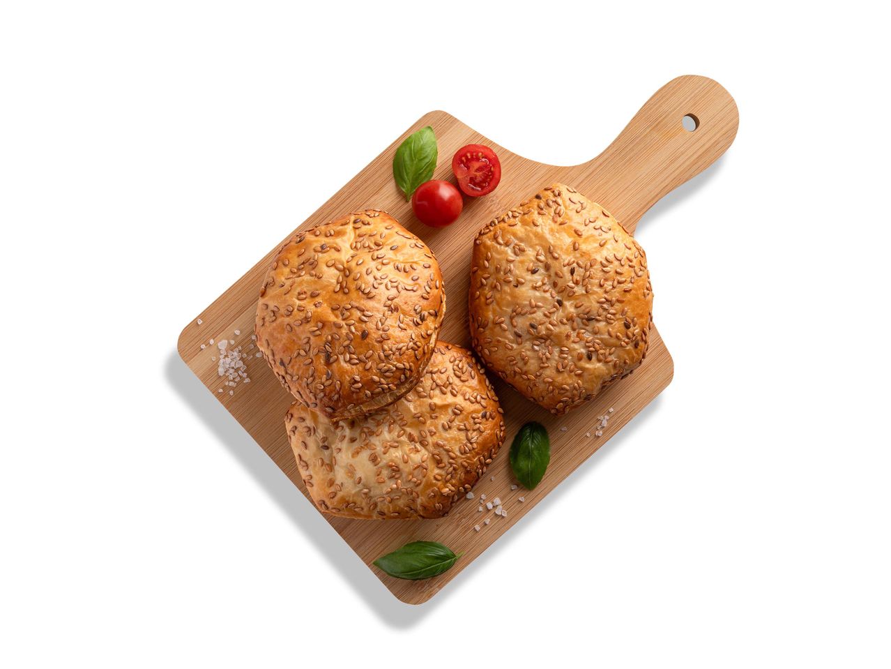 Szezámmagos péksütemények fából készült vágódeszkán, paradicsommal és bazsalikommal.